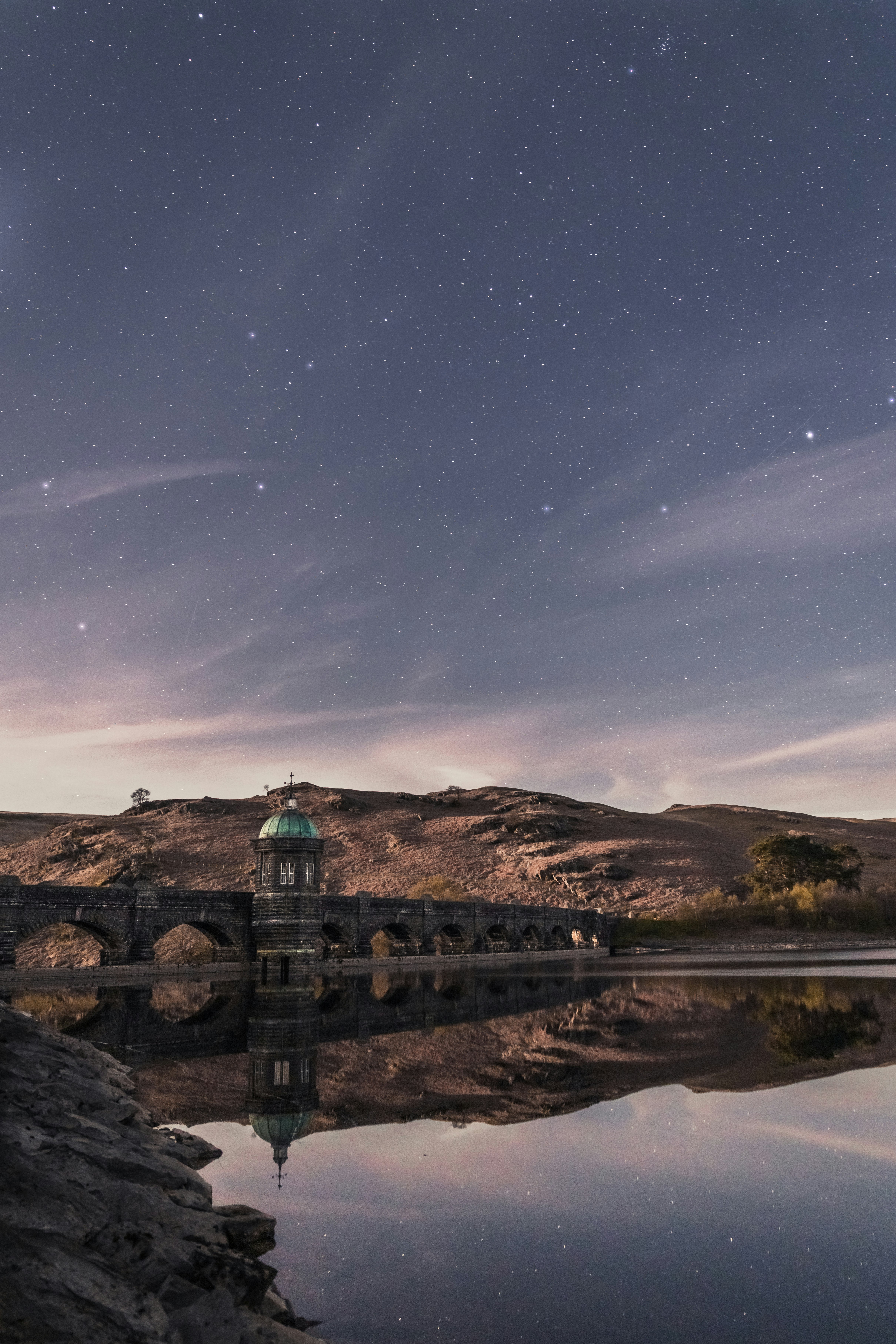 calm body of water and mountain under starry sky